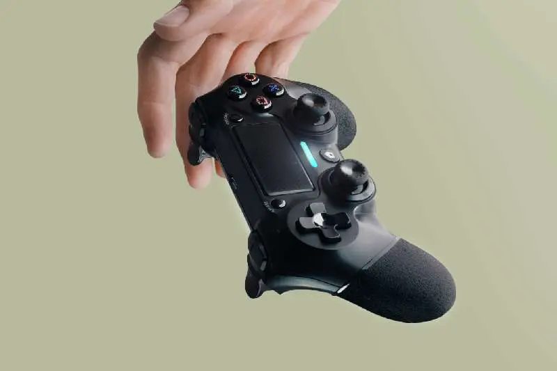 The hand holds a black gamepad for playing computer games